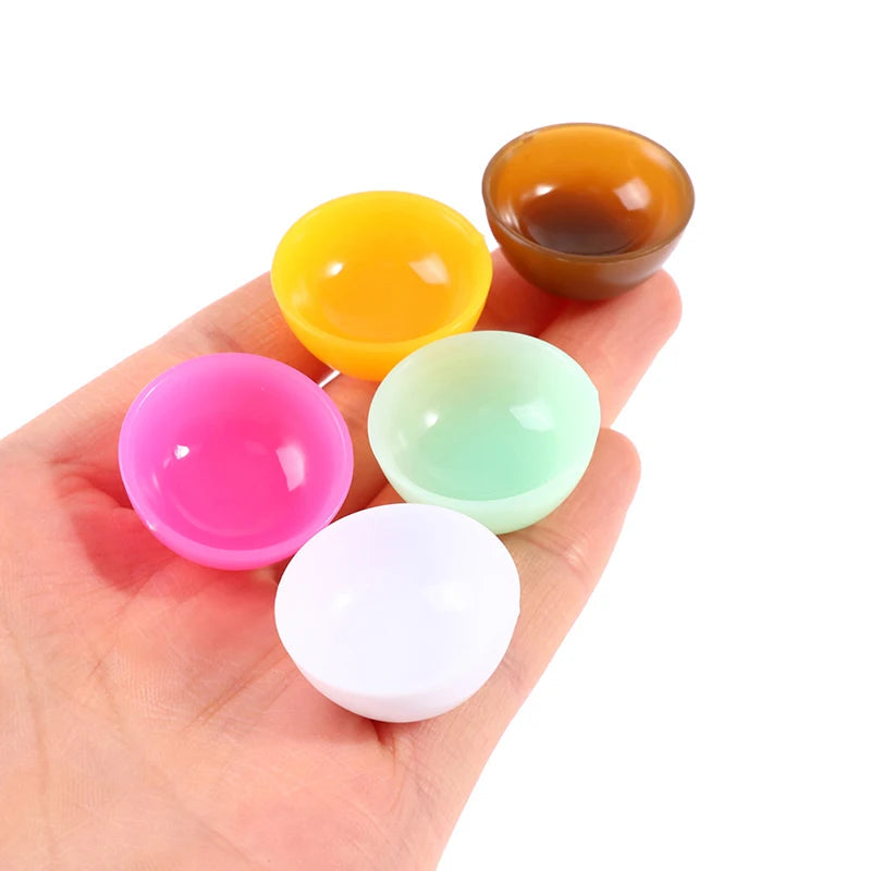 Colorful miniature dollhouse bowl set in a hand, featuring pink, yellow, mint, white, and brown bowls. Perfect for dollhouse decor.