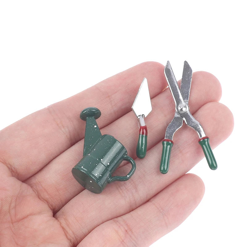 Miniature gardening tool set featuring tiny watering can, trowel, and shears on a hand, ideal for dollhouse gardens.