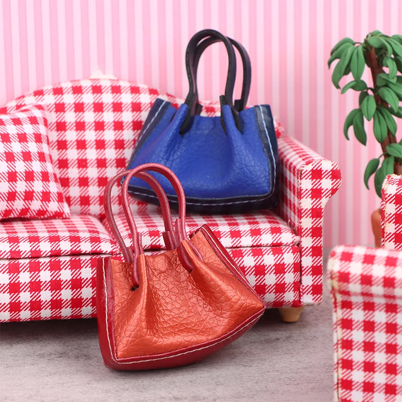 Miniature leather handbags in red and blue on a checkered dollhouse sofa, perfect for collectors and doll enthusiasts.