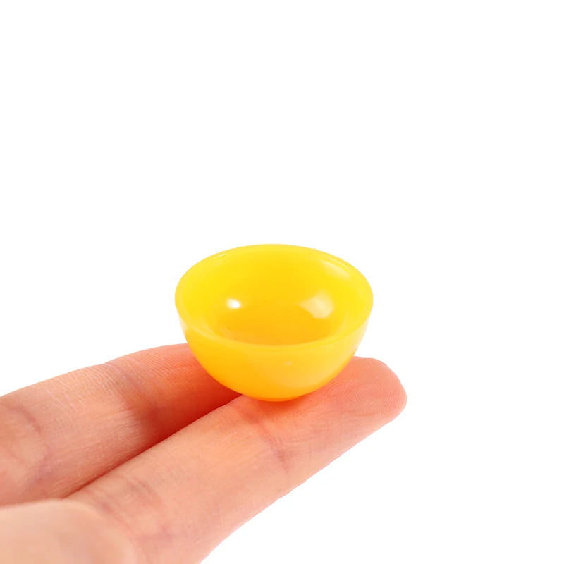 Yellow miniature dollhouse bowl held between fingers, perfect for realistic kitchen or dining room decor in dollhouses.