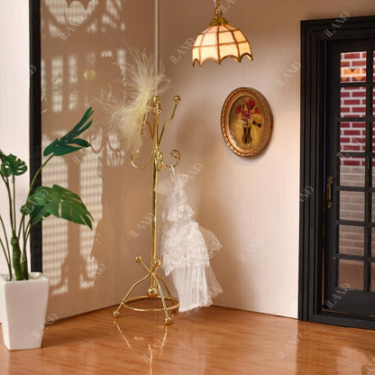 Miniature golden coat rack in 1:12 scale dollhouse, elegantly placed beside a decorative mirror.