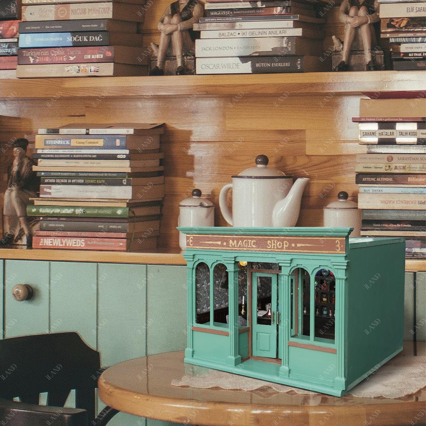 Miniature coffee shop dollhouse in teal, set against a warm, cozy backdrop of books and vintage decor.