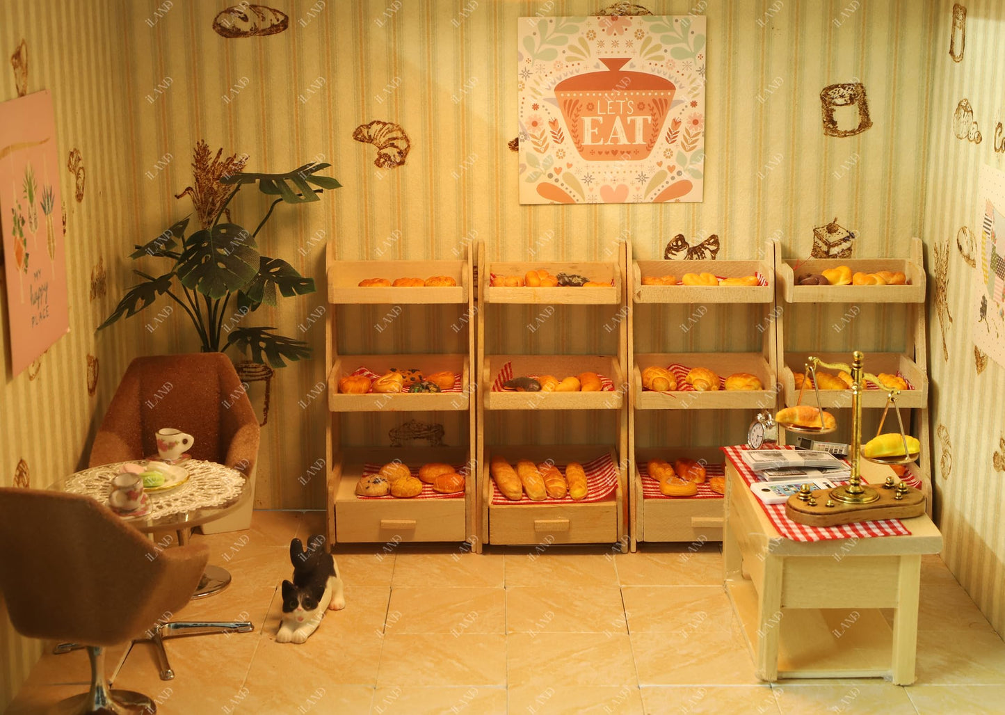 Miniature coffee shop scene in iLAND 1/12 scale dollhouse, featuring wooden shelves with pastries and cozy seating.