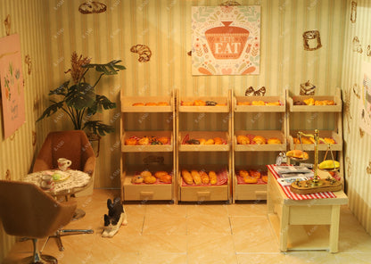Miniature coffee shop scene in iLAND 1/12 scale dollhouse, featuring wooden shelves with pastries and cozy seating.
