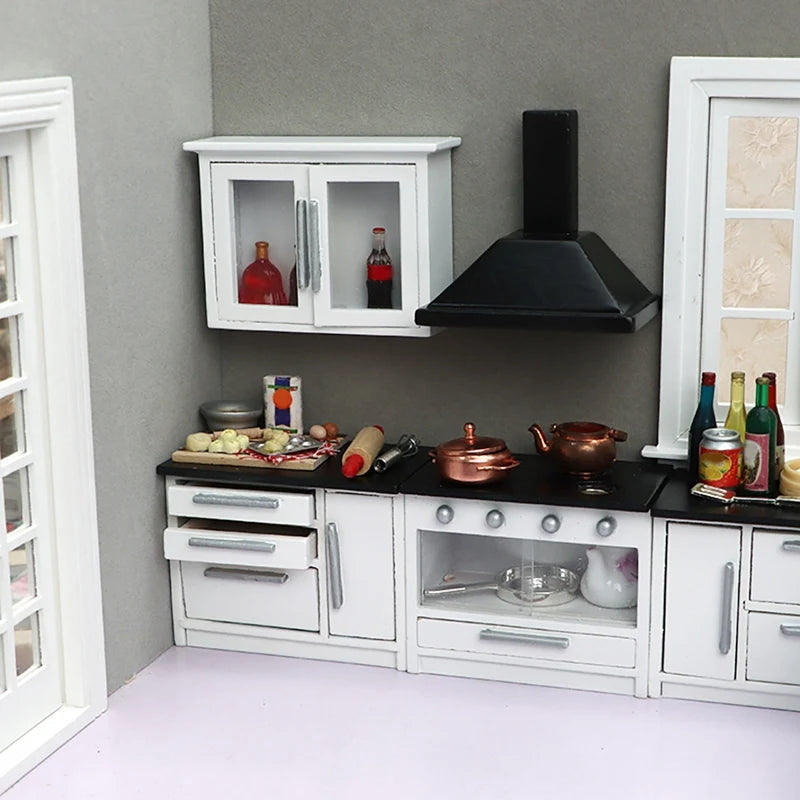 Modern 1:12 dollhouse kitchen set with white cabinets, mini appliances, cookware, and food items on black countertops.