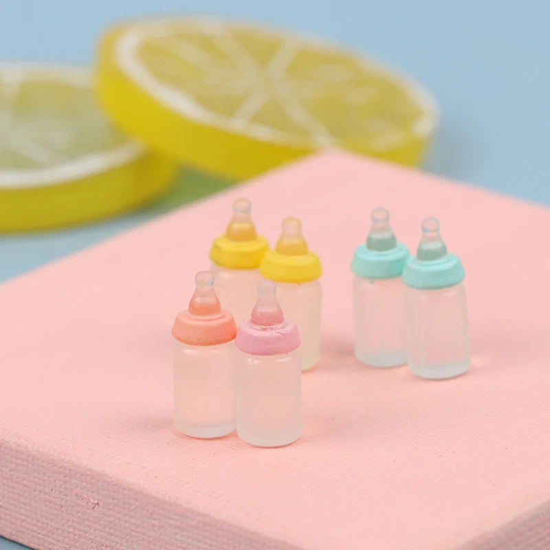 Colorful miniature baby bottle set for dollhouses, perfect for realistic play scenes. Pastel caps add charm to tiny nurseries.