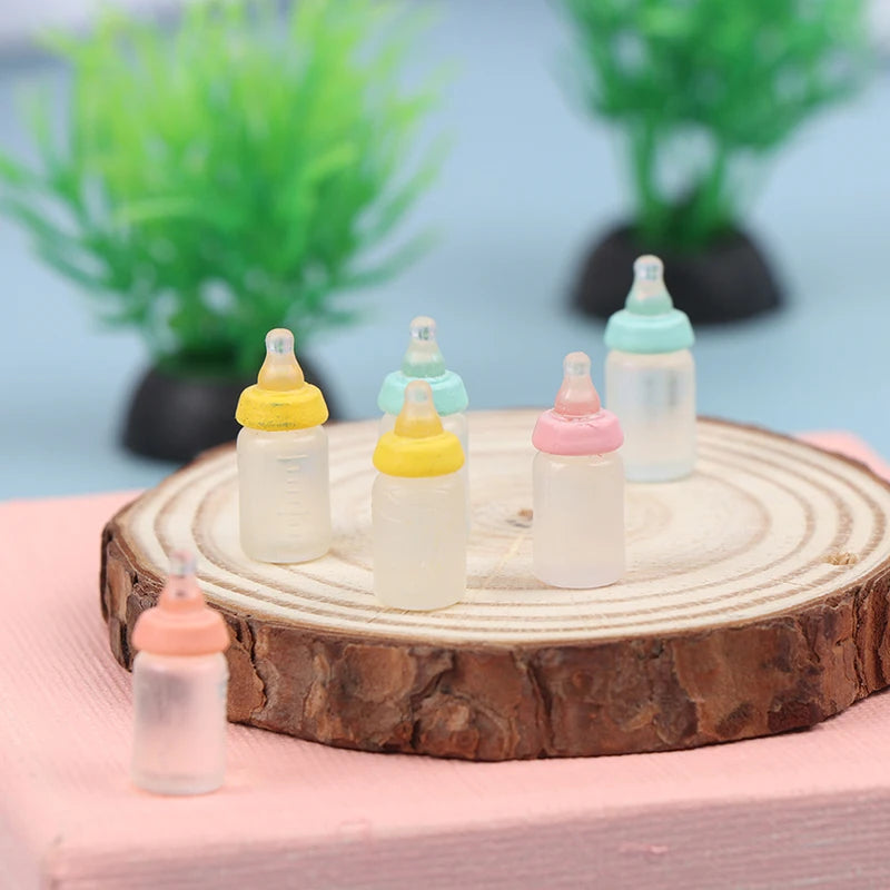 Miniature baby bottles with colorful caps displayed on a wooden slice, perfect for dollhouse nursery decoration.