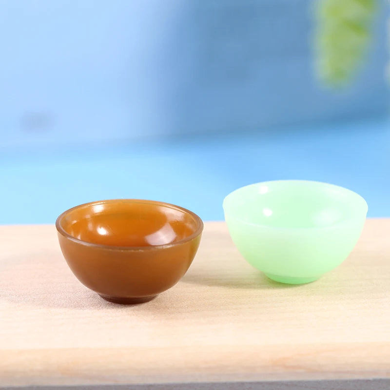 Two miniature dollhouse bowls, one brown and one green, on a wooden surface. Perfect for dollhouse kitchen decor.